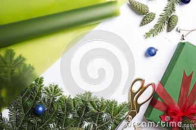 Top view of white table, process of wrapping Christmas gifts. Fir tree, gift box, Christmas ornaments, wrapping paper.Empty space Stock Photo