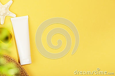 Top view of white unbranded tube, starfish, sunglasses and green plant. Blank tube for sunscreen, moisturizing lotion or Stock Photo