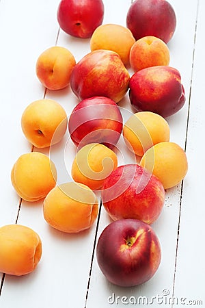 Top view of white wooden background with juicy orange apricots and bright fresh red nectarines and peaches. Stock Photo