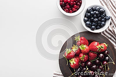 Top view of whole cranberries and blueberries on bowl, strawberries and cherries on plate. Stock Photo