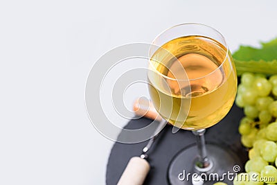 Top view on wineglass of white wine with grape, cork and corkscrew on gray background. Holiday celebration concept Stock Photo