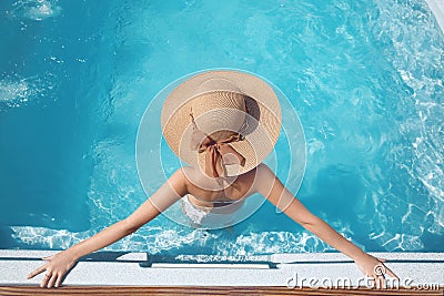 Top view of Woman in beach hat enjoying in swimming pool on luxury tropical resort. Exotic Paradise. Travel, Tourism and Vacation Stock Photo