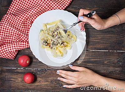 Top View of Woman Eating pasta with Mushrooms on wood table Stock Photo