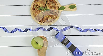 Top view of woman hand selection of healthy eating with green apple and dumbbell Stock Photo