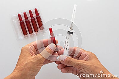 Top view of woman hands holding 2 ml ampoule with vitamin group B for injection and 5 ml syringe barrel Stock Photo