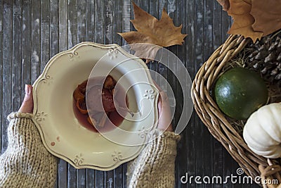 Top view of woman hands holding a vintage bowl with drunken pears dessert. Autumn composition Stock Photo