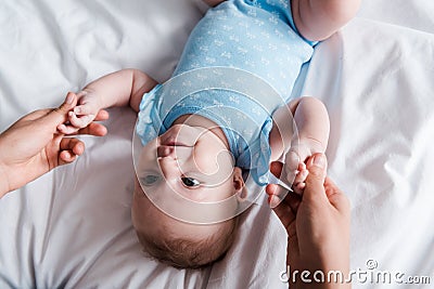 View of woman holding hands of infant in blue bodysuit Stock Photo