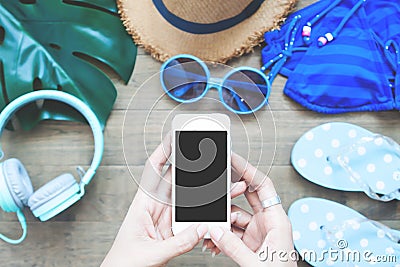 Top view of woman`s hands using smartphone with summer items on Stock Photo