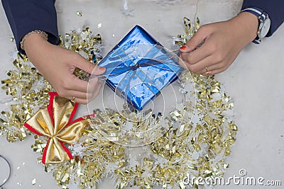 Top view woman s hands wrapping christmas gift, close up, unprepared chistmas presents on cement table at indoors home park Stock Photo