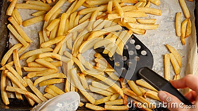 Top view of woman stirring french fries on baking pan with spatula. Fast food, healthy nutrition, cooking in oven Stock Photo
