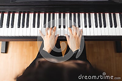 Top view of woman's hands playing piano by reading sheet music. Stock Photo