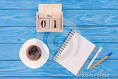 top view of wooden calendar with date of 1st may, coffee cup, blank textbook and pens, international workers day concept Stock Photo