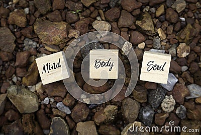Top view of wooden cube written with Mind Body Soul on a brown rock background Stock Photo