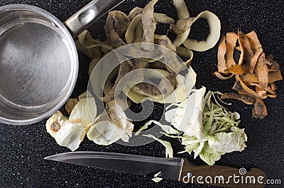 Top view of leftover vegetable peelings, knife and pot on the black kithcen table Stock Photo