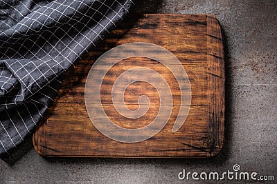 Top view of wooden dark brown vintage chopping board on dark metallic background with black checked cloth partial Stock Photo