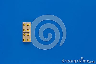 Top view of wooden dominoes gaming double piece with four spots on with copy space on the blue background Stock Photo