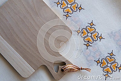 Top view of a wooden kitchen board. The board is on an old embroidered fabric. The board is clean and there is nothing on it Stock Photo