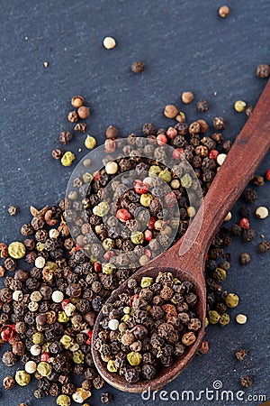 Top view of a wooden spoon full of allspice seeds on dark background, shallow depth of field, front focus Stock Photo