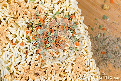 Top view of a wooden tray with chopsticks next to a bowl of instant noodles topped with spices Stock Photo