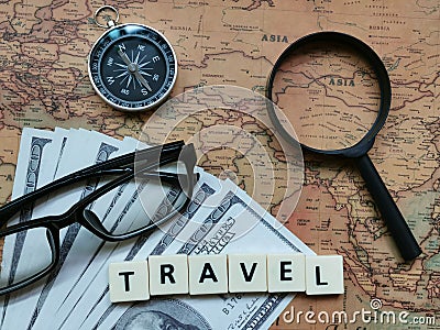 Top view word travel with compass, eye glasses, fake money and magnifier on world map. Stock Photo