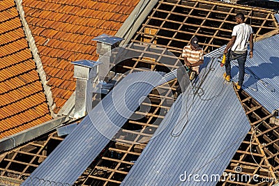 Top view of a worker placing metal sheets on a house to renovate the roof of a commercial point Editorial Stock Photo