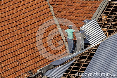 Top view of a worker placing metal sheets on a house to renovate the roof of a commercial point Editorial Stock Photo