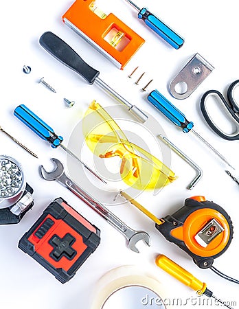 Top view of working tools, wrench, screwdriver, level, tape measure, bolts, and safety glasses on a white background. Stock Photo