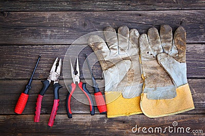 Top view of worn work gloves and assorted work tools over wooden background Stock Photo