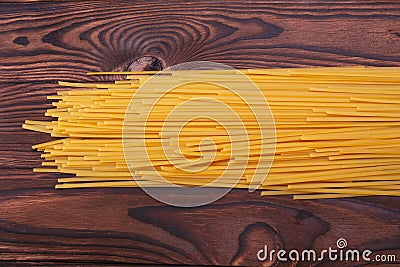 A top view on yellow pasta. Uncooked macaroni on a wooden background. Tasty vegetarian noodles. Homemade dinner concept. Stock Photo