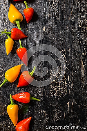 top view of yellow and red hot chili peppers on cracks black background, close up Stock Photo