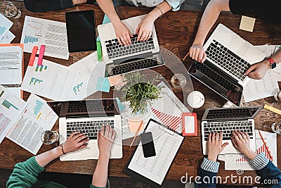 Top view of young coworking people are working on laptops and paper documents. Group of college students using laptop while sittin Stock Photo
