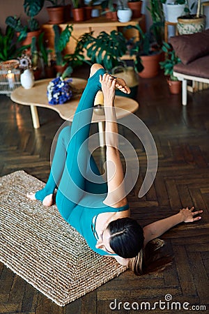 Top view of young sporty woman practicing stretching exercise doing one armed swastikasana yoga pose Stock Photo