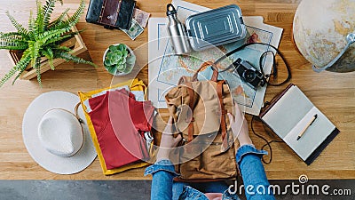 Top view of young woman packing for vacation trip holiday, desktop travel concept. Stock Photo