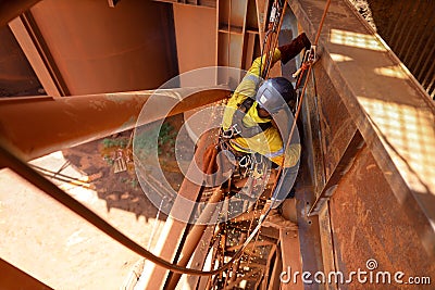 Tope view abseiler rope access repairer hanging in fall restraint position performing oxy acetylene cutting metal beam Stock Photo