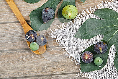 Tope view of ripe figs scattered around a wooden table with leaves and a wooden spoon Stock Photo