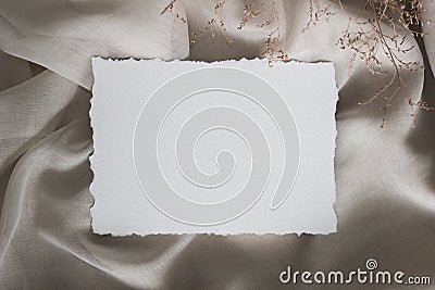 Torn edge paper card on linen cloth with tiny flowers, closup. Wedding stationery mockup. Calligraphy template Stock Photo