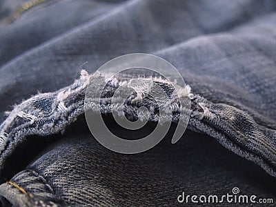 Torn edges of a blue jeans background. Old ripped worn faded jeans background. Distressed grunge denim. Macro. Stock Photo