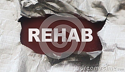 Torn foil paper with word Rehab. Healthcare medicine concept. Addictions concept Stock Photo