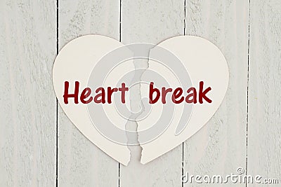 Torn heart-shape card on weathered wood background with text Heartbreak Stock Photo