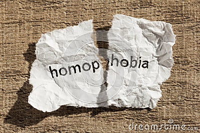 Torn paper written homophobia over wood table. Concept of old an Stock Photo