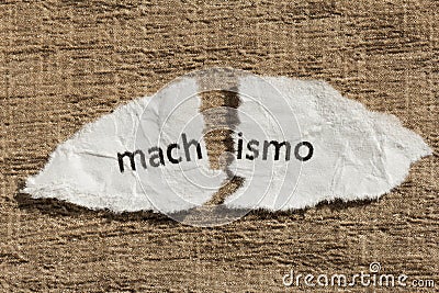 Torn paper written machismo, portuguese and spanish word for chauvism, over wood table. Concept of old and abandoned idea or Stock Photo