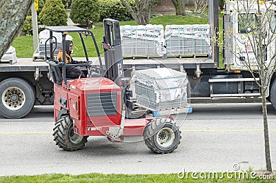 Toronto, Canada - April 28, 2020: Workman Driving a Red Forklift to Move a Pile of Concrete Patio Stones on a Suburban Street #2 Editorial Stock Photo