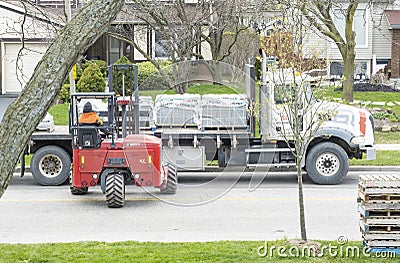 Toronto, Canada - April 28, 2020: Workman Driving a Red Forklift to Move a Pile of Concrete Patio Stones on a Suburban Street #4 Editorial Stock Photo