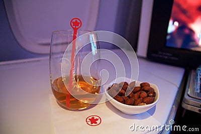 TORONTO, CANADA - JAN 28th, 2017: Air Canada Business class in a passenger plane. A glass of whisky and some warm nuts Editorial Stock Photo