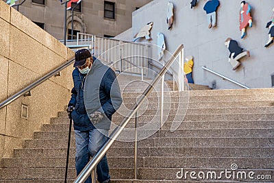 TORONTO, CANADA - JANUARY 23, 2021: OLDER MAN WEARING MASK ON STEPS DURING COVID-19 PANDEMIC. Editorial Stock Photo