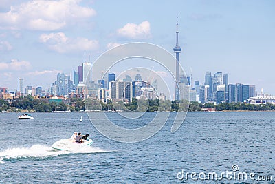 Toronto, Canada - June 28, 2020 : People enjoying the water in a boat on the lake, with the Toronto skyline in the background. Editorial Stock Photo
