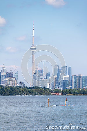 Toronto, Canada - June 28, 2020 : Women enjoying the water paddle boarding across the lake, with the Toronto skyline in the back Editorial Stock Photo