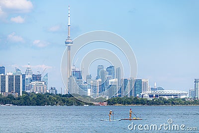 Toronto, Canada - June 28, 2020 : Women enjoying the water paddle boarding, with the Toronto skyline in the backgr Editorial Stock Photo