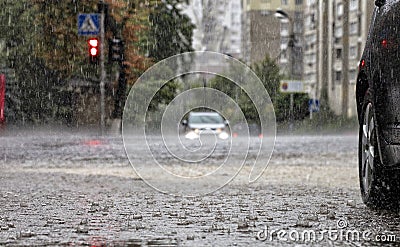 Torrential rain on the road and on the sidewalk watering cars standing at the crossroads Stock Photo