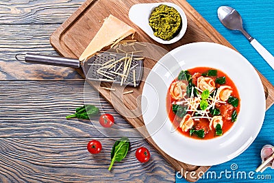 Tortellini soup with italian sausages, spinach, tomato, parmesan cheese , pesto-sauce Stock Photo